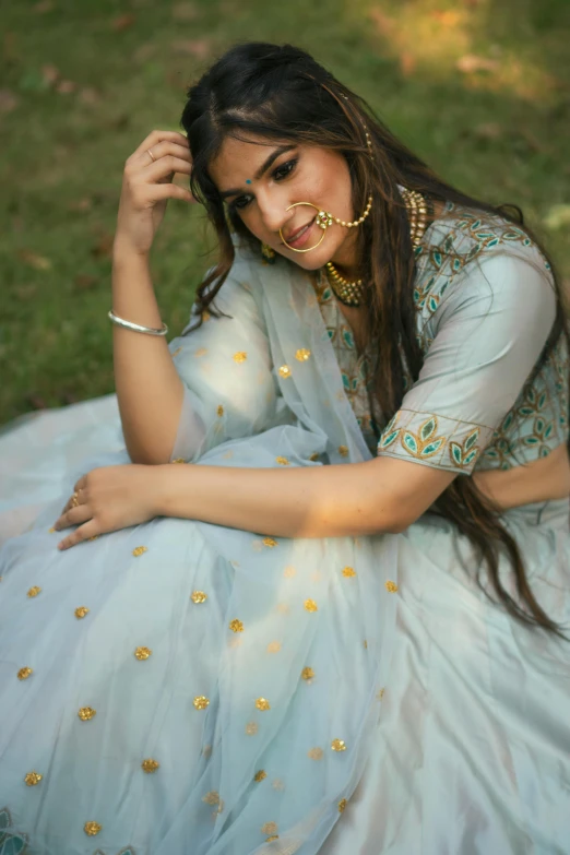 a girl wearing some jewelry sitting in the grass