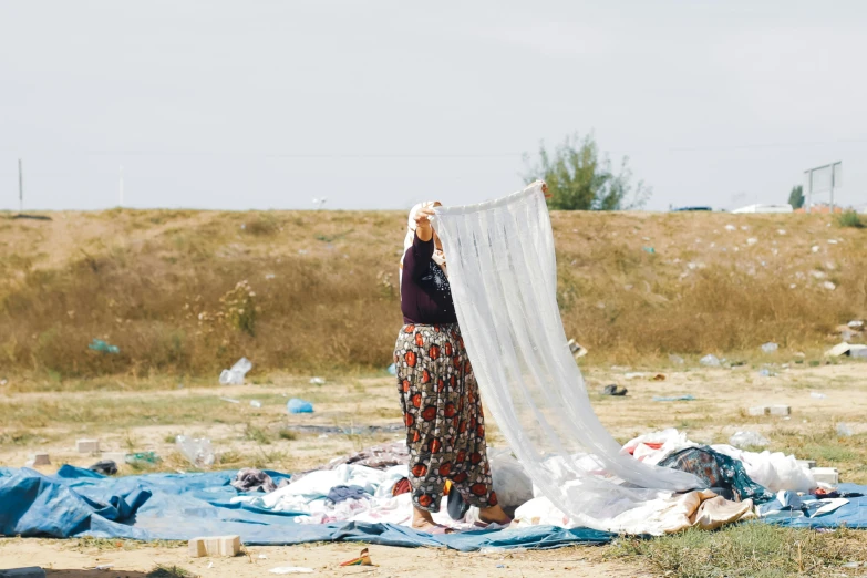 a woman is walking across a field next to several tents