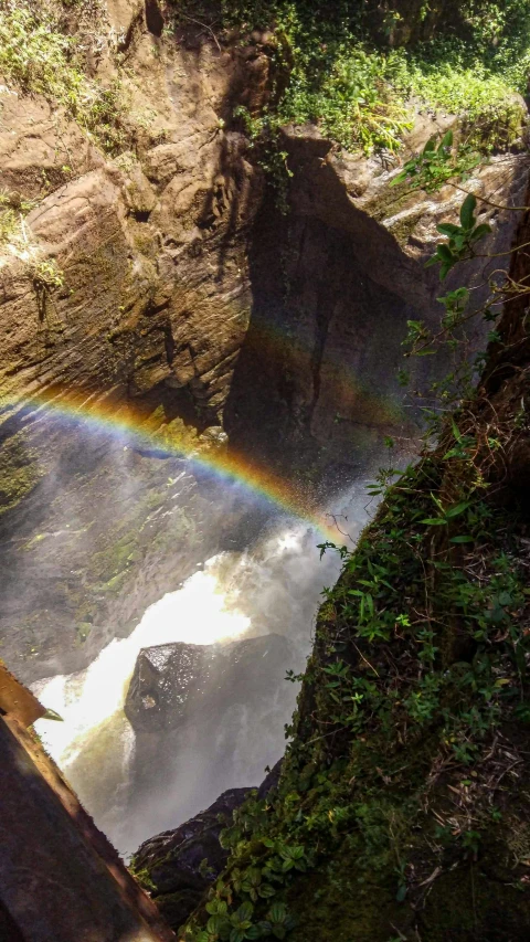 a rainbow shines in the sky over a waterfall