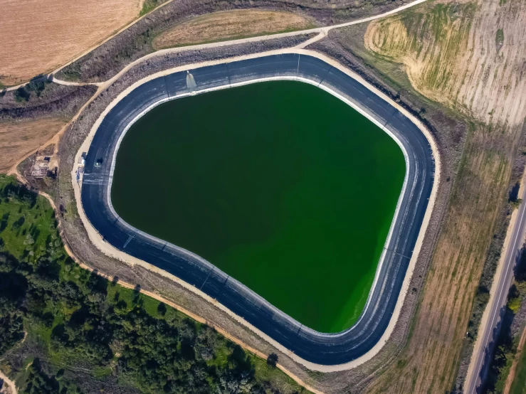 a green lake with a circular shape surrounded by fields and other land