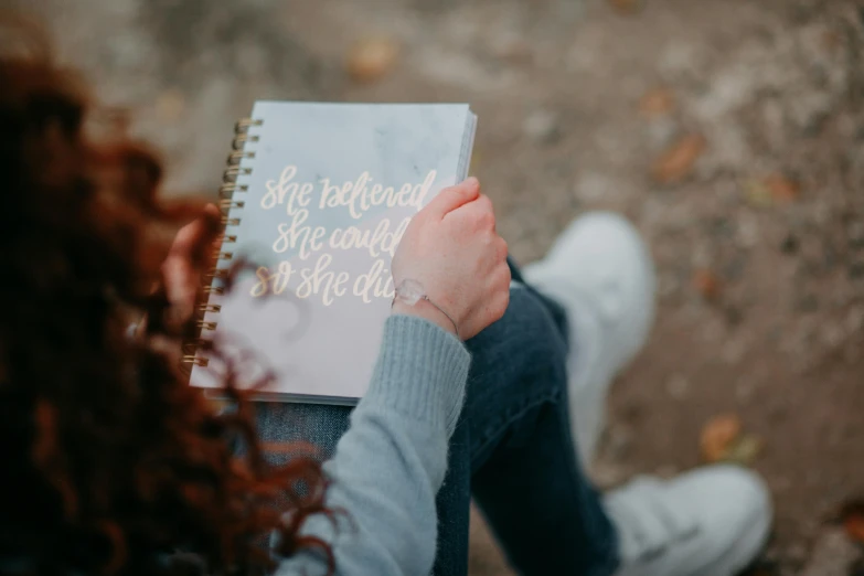 a woman is holding a notebook in front of her face