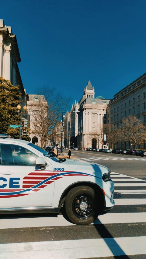 a police car on the road with people walking around