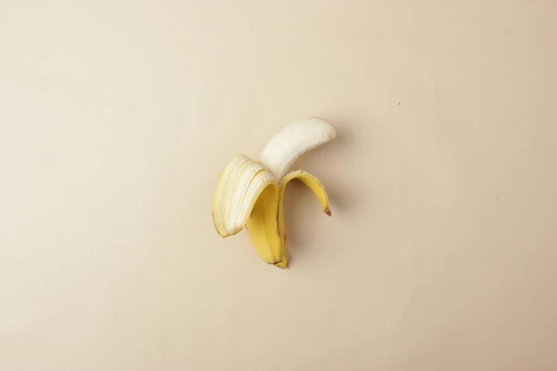 a single peeled banana hanging on a wall