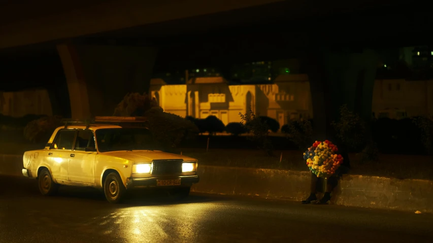 a woman standing in the middle of a street while her yellow taxi sits parked