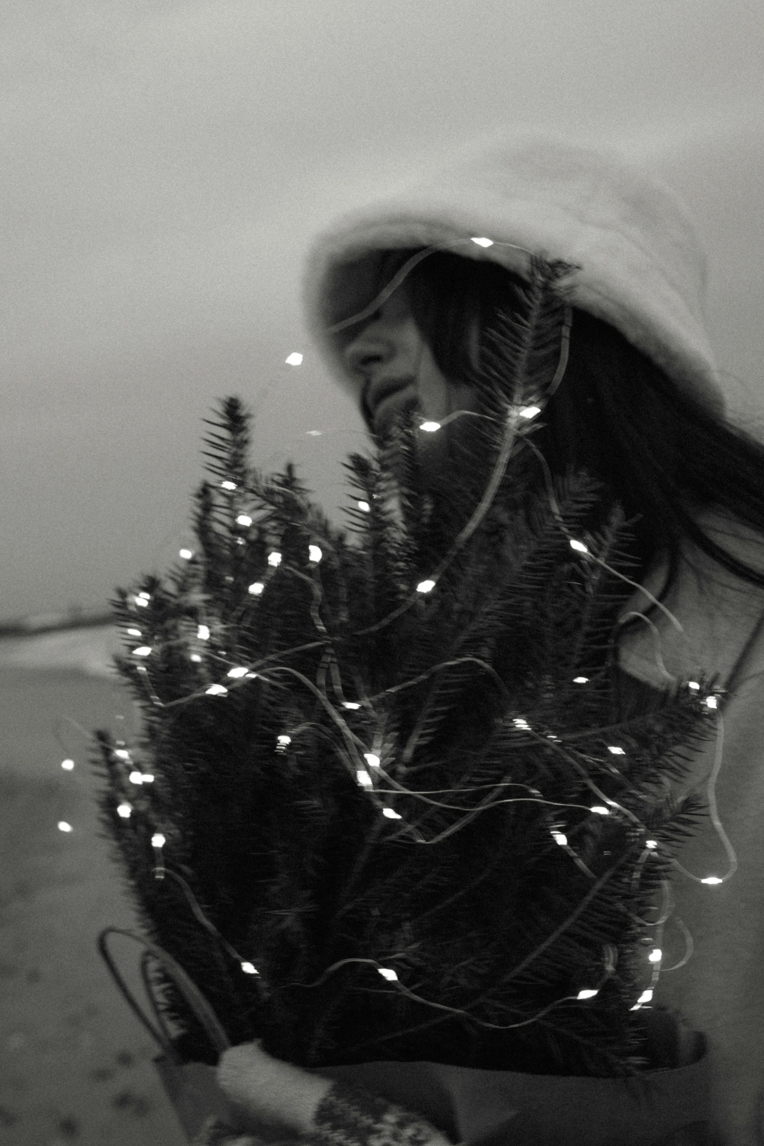 a woman holding onto a christmas tree on the beach