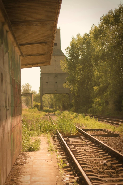 a railroad track runs along a wall near an abandoned factory