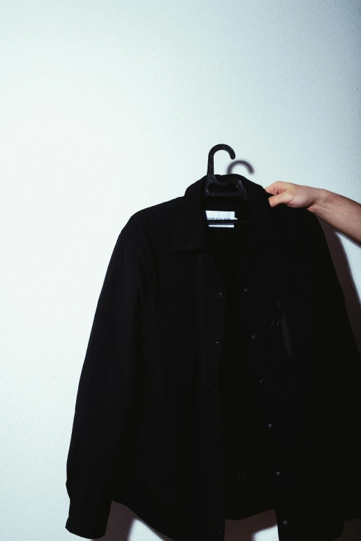 a hand holding a black jacket with white background