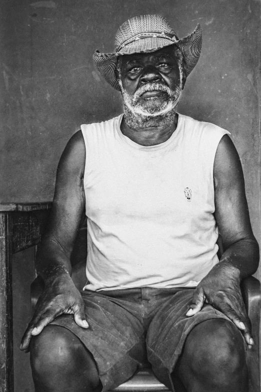 an old man with a straw hat sitting on top of a chair