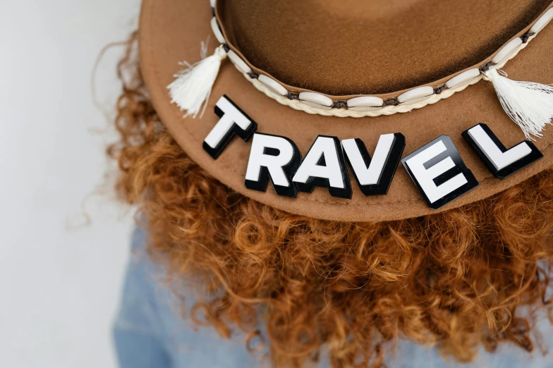 a hat that says travel hanging over a curly hair