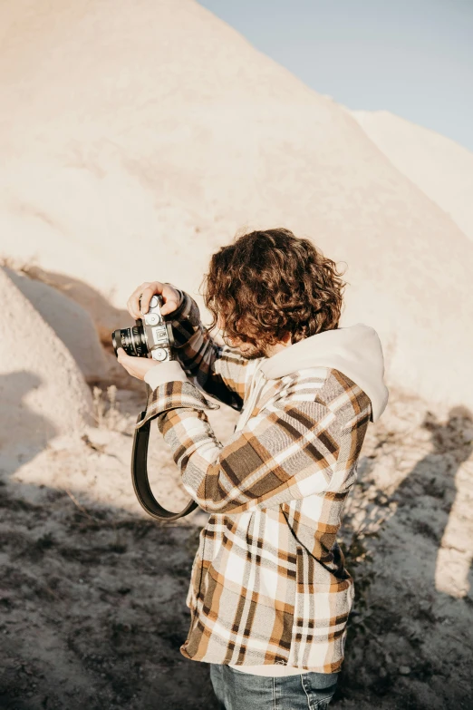 a man with curly hair takes a picture in the desert