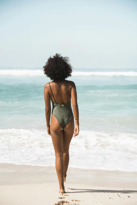 a woman in a bikini walking along the beach