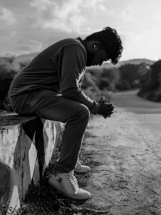 a man is sitting on a rock in the middle of the road