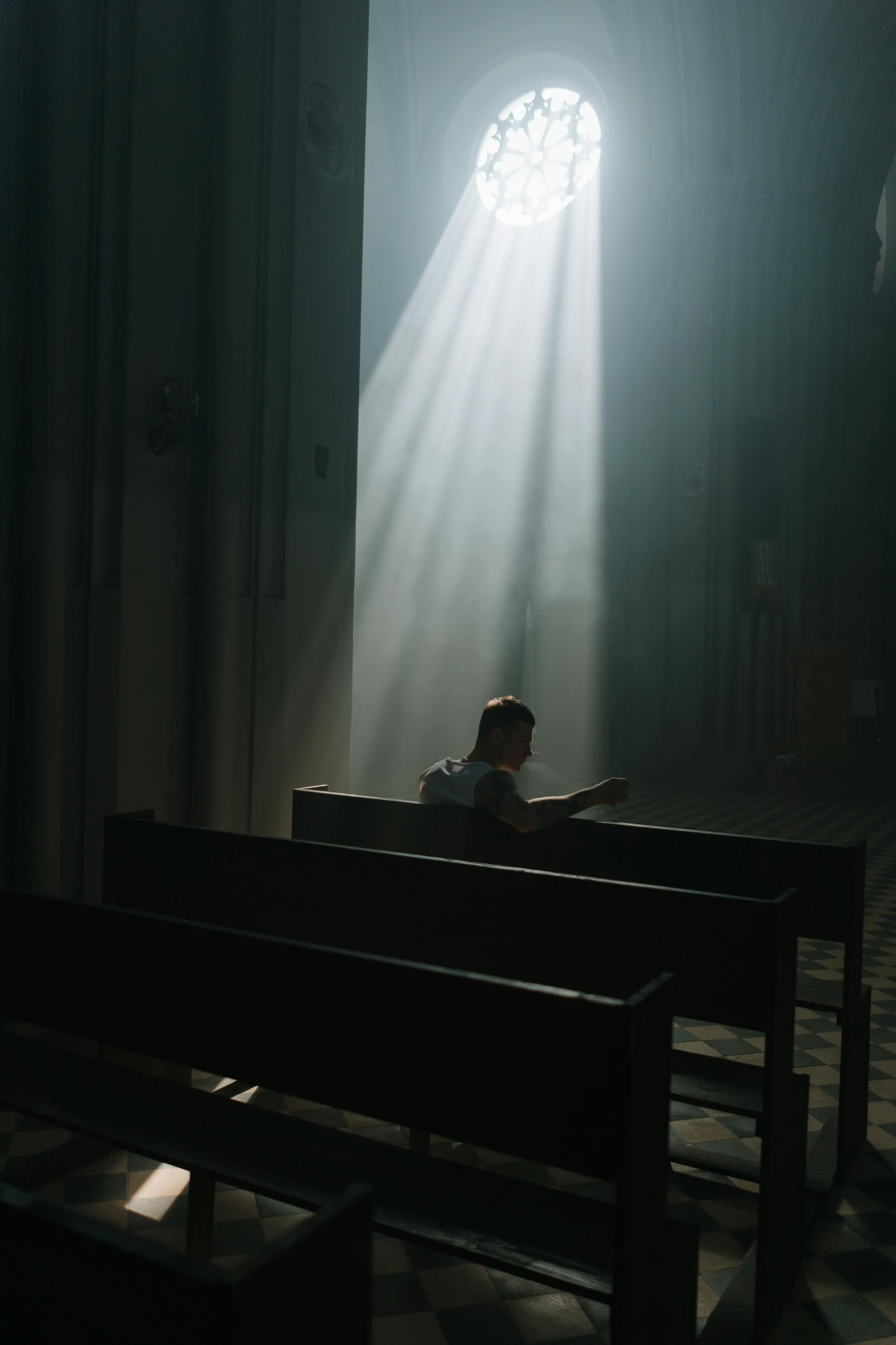 a person sits on the pews under a beam of light