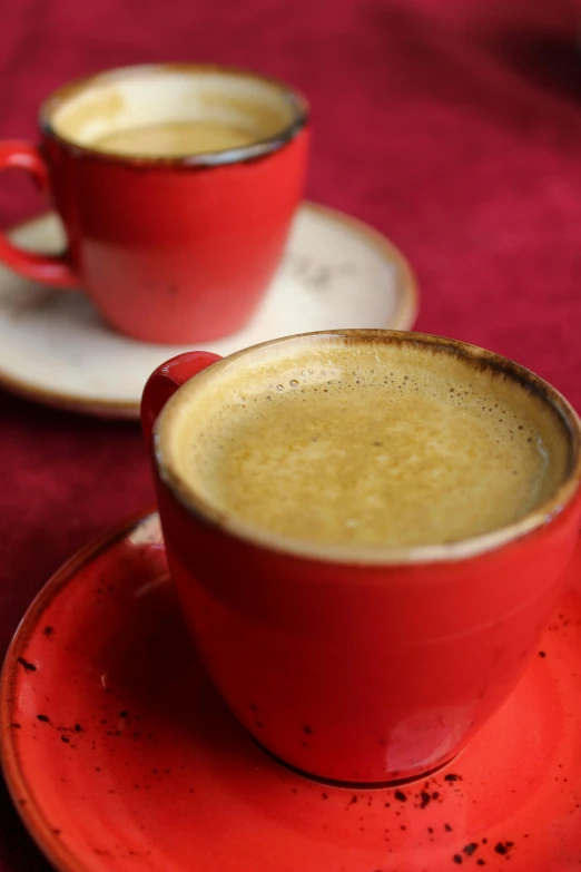 a red cup with saucer on two plates