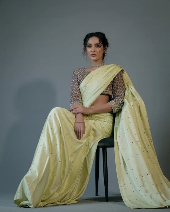 a woman in a yellow sari sits on a chair