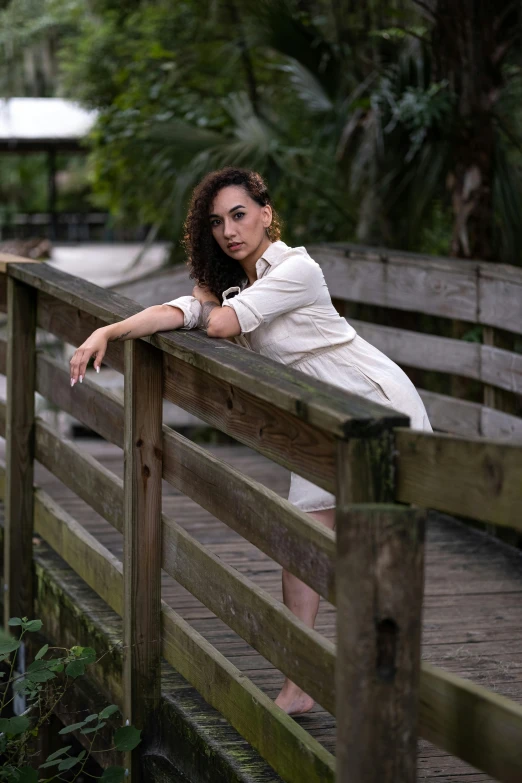 a woman leans against a rail on a wooden bridge