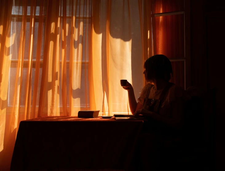 a woman looks at her cell phone while sitting in front of a window