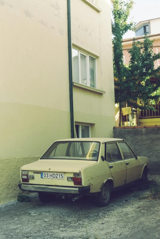 a tan car parked next to a beige building