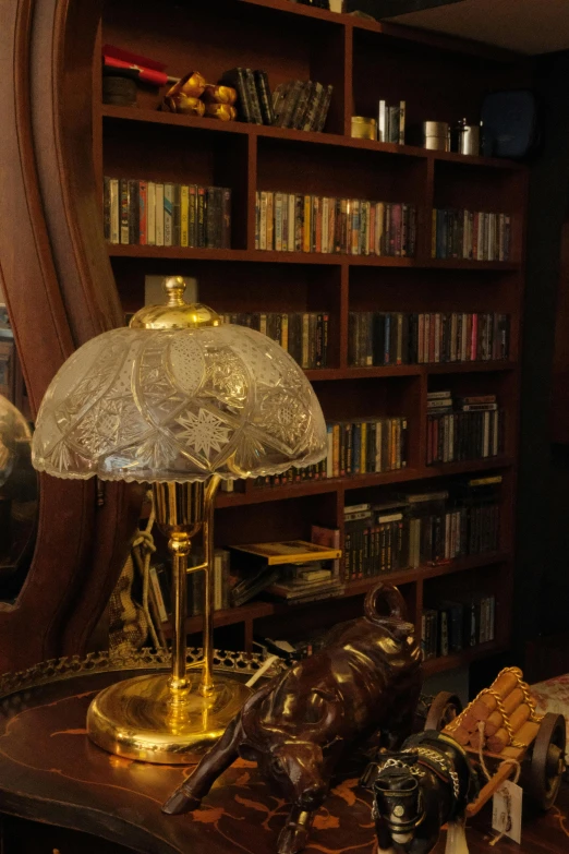 a golden table lamp is in front of a book shelf