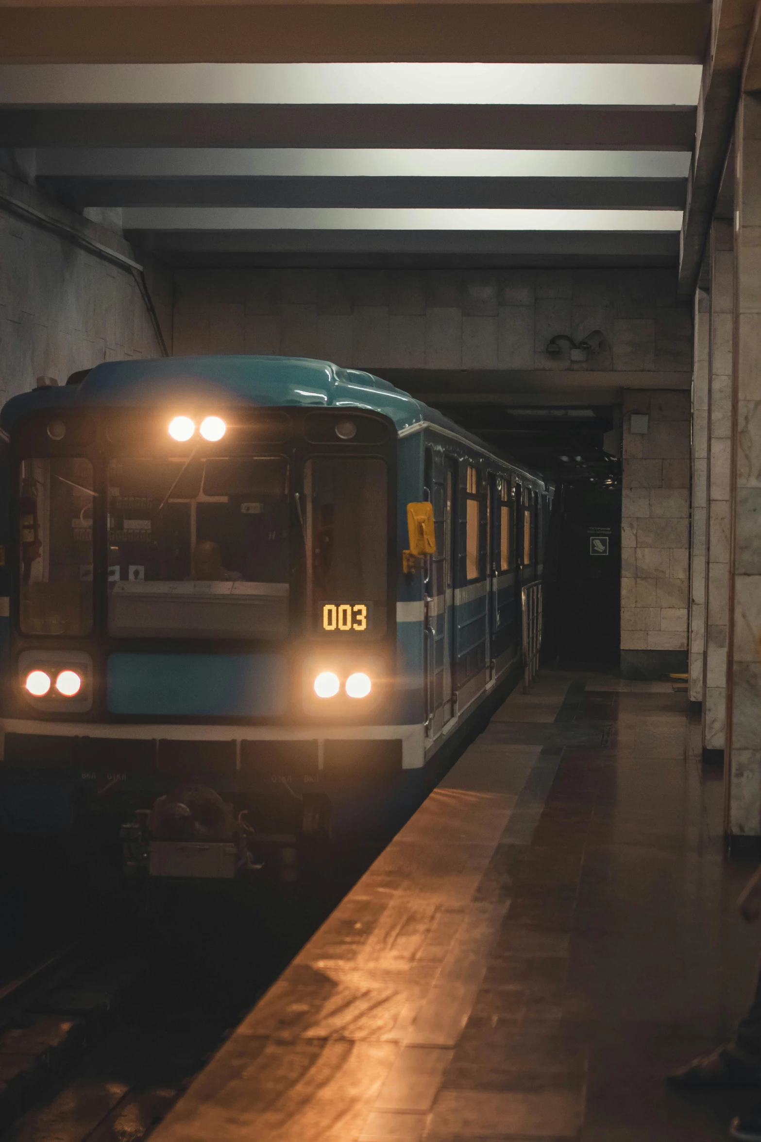 a subway train with headlights on at the station