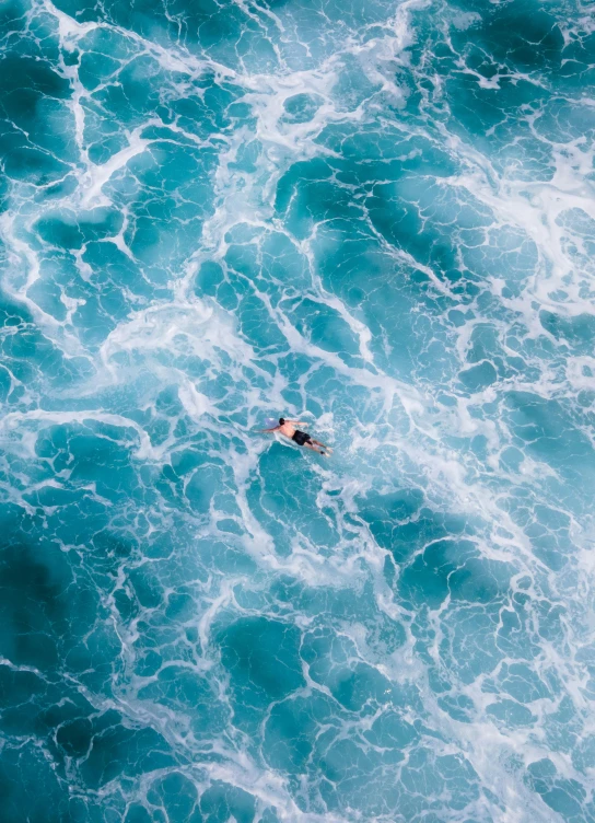 an aerial view of a swimmer in the ocean