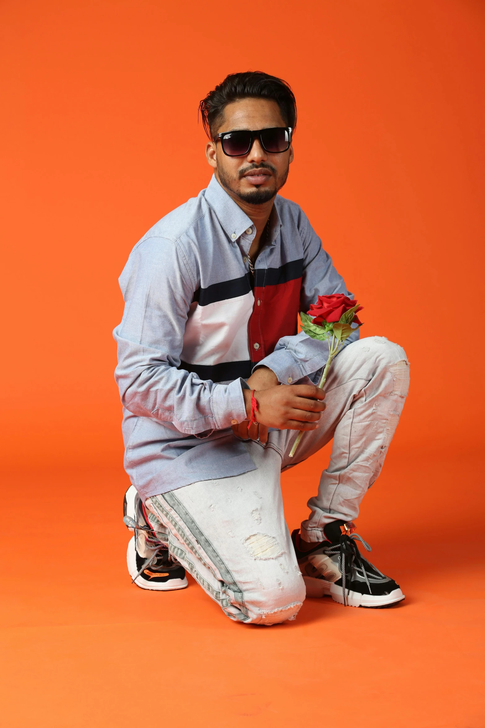 a man squatting while holding flowers