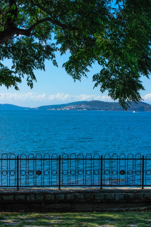 two people sit on the bench near water and trees