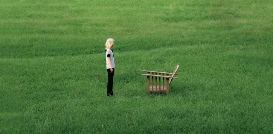 a woman standing on the grass next to a chair