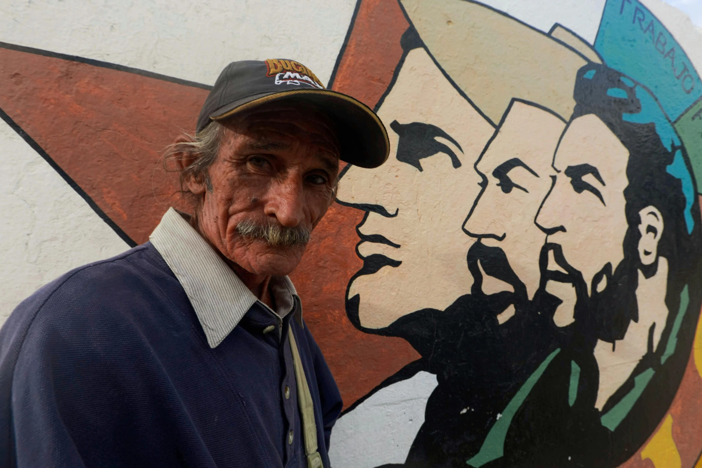 a man standing in front of a mural wearing a hat