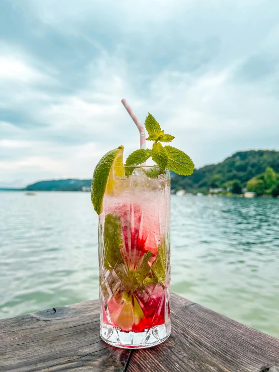 two mojitos on a table overlooking water and trees