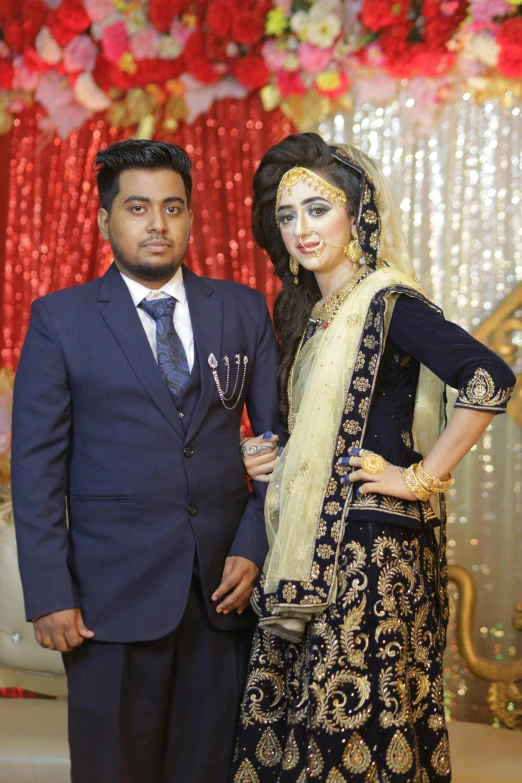 an indian couple dressed in traditional attire poses for the camera