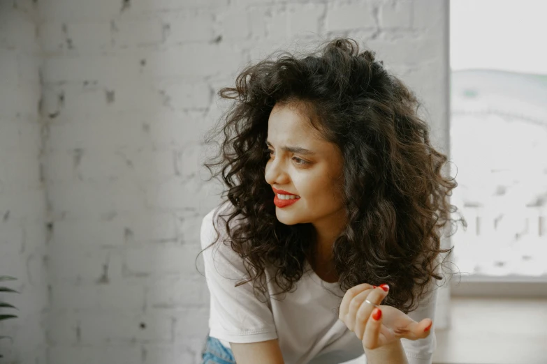 woman in white tee - shirt sitting with one hand on the other