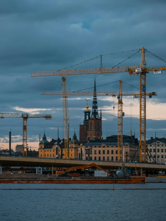 a few cranes on a river and some buildings