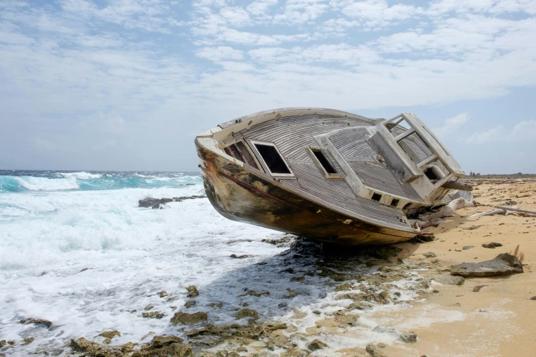 there is an old boat on the beach with the ocean in the background