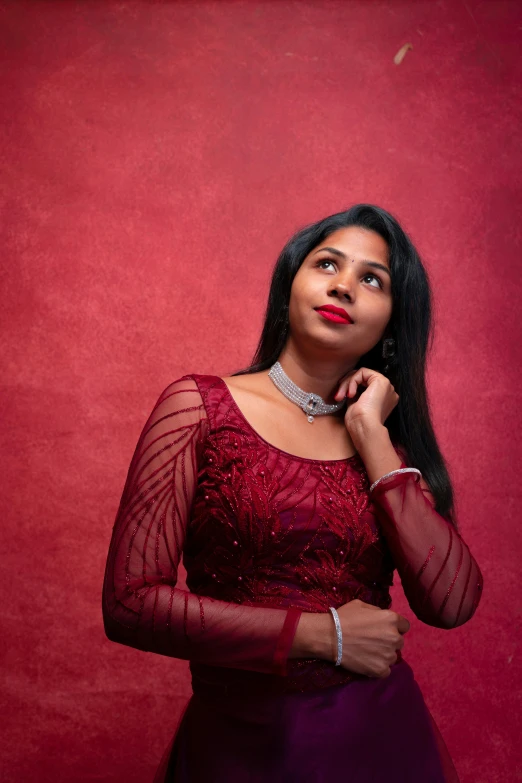 woman in a purple dress standing in front of a red wall