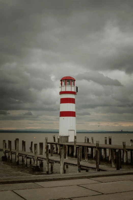 a red and white lighthouse with cloudy sky in the background