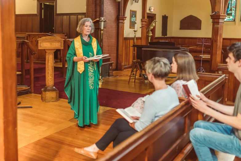 a woman in a green robe is giving a speech at a service