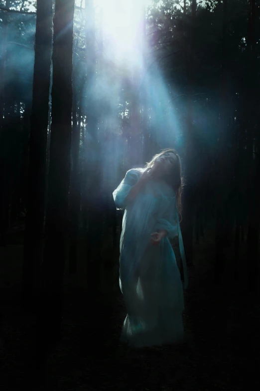 the woman is walking through the dark forest