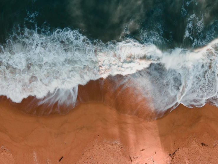 waves breaking into a sandy beach and making it appear to be in the water