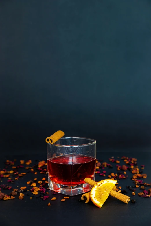 a glass with an orange slice and ice on the edge, surrounded by a pile of bits of food