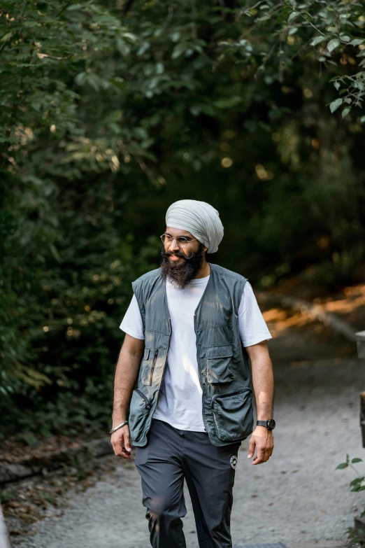 a man walking in the woods wearing a hat and vest