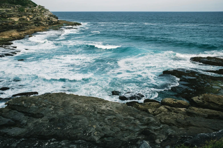 a wave crashing into rocks along the shore