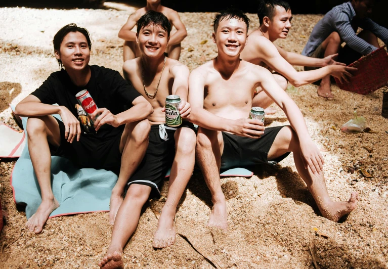 three young men sitting on a blanket on a beach