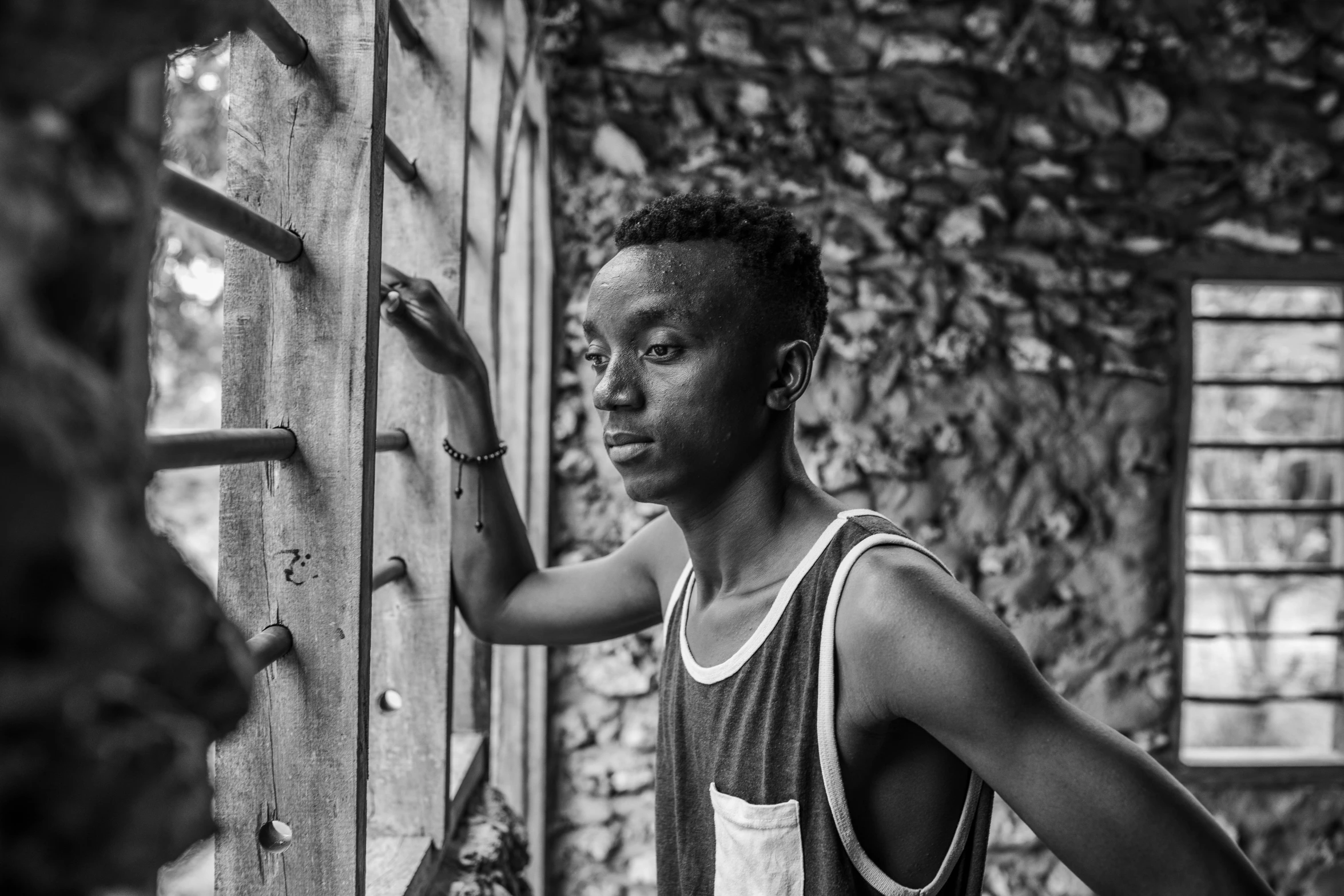 an african man holding onto a wooden wall