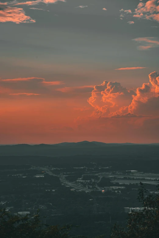 a view of an orange sunset over mountains and city below