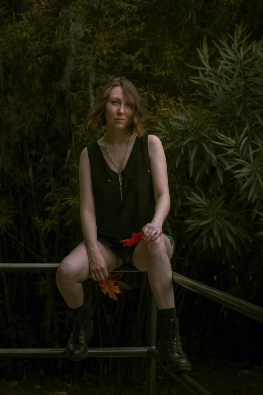 a woman sits with a small flower in her hand