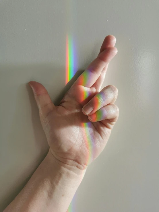 someone is holding out their hand to the side of the room with a rainbow pattern on it