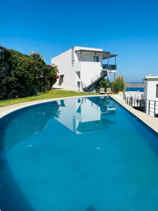 a long swimming pool in front of two white buildings