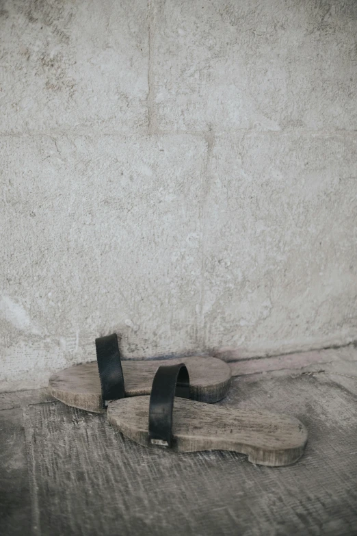 a wooden sandal sitting on the ground in front of a cement wall