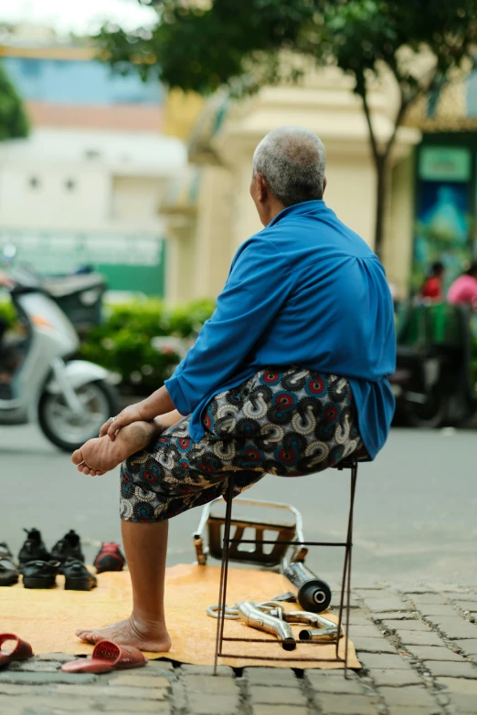 an elderly man sitting down with some shoes on the floor